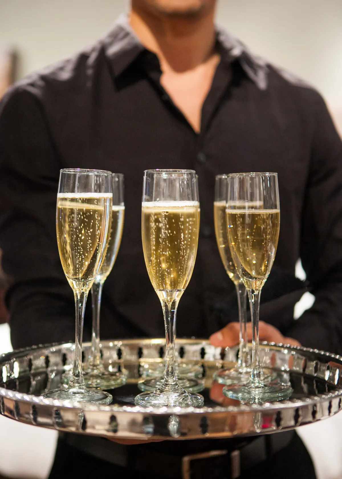 server holding glasses of sparkling wine