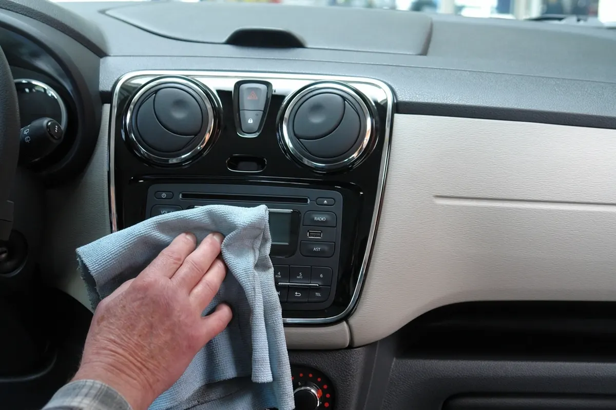 hand wiping a car dashboard with a microfiber cloth