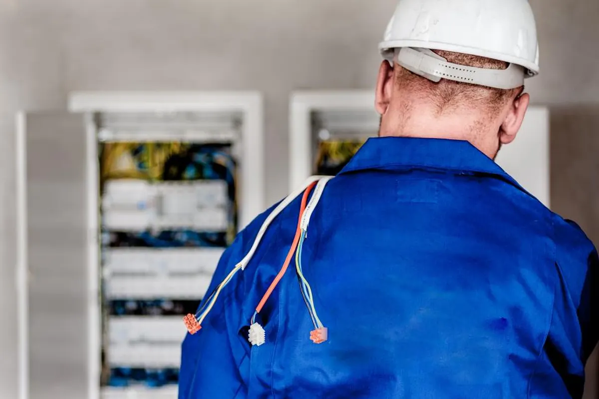 electrician in a hard hat working on a breaker panel