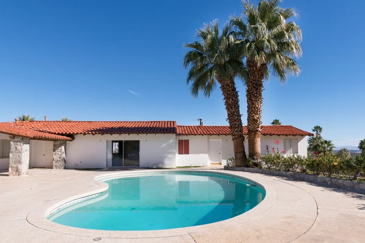 single-story home with a pool and palm trees