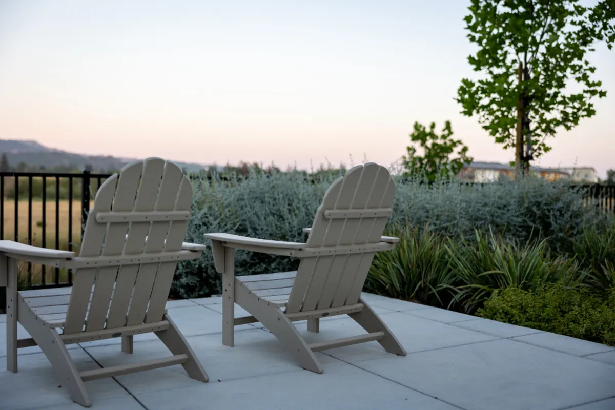 patio with two Adirondack chairs overlooking a garden at dusk