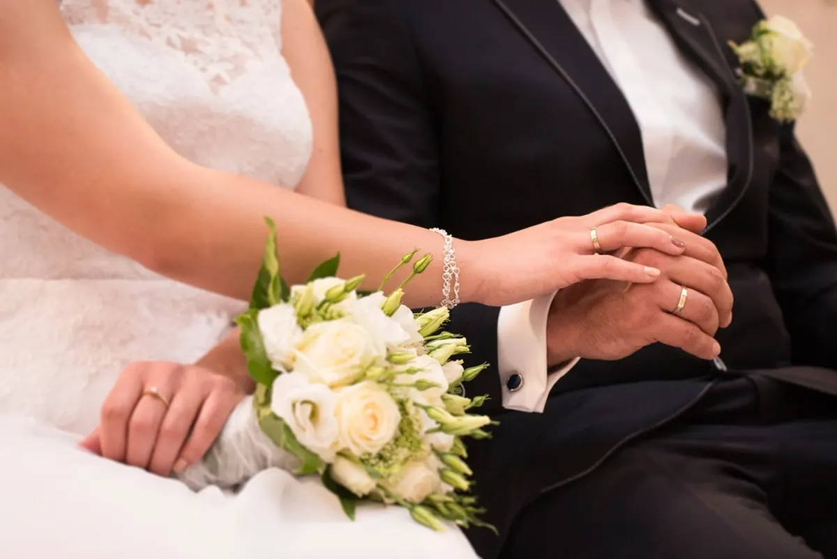 couple holding hands with a white bouquet