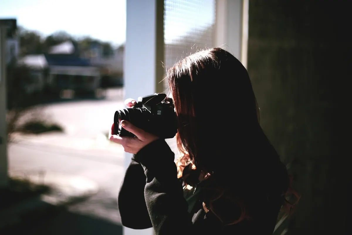 woman photographing through a window with a camera