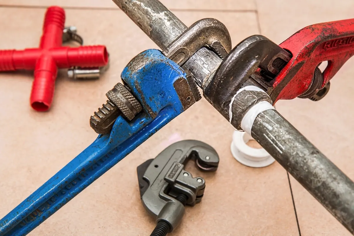 plumbing wrenches and pipe fittings on a floor