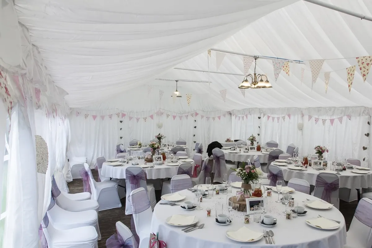 wedding reception tent set with round tables and white linens