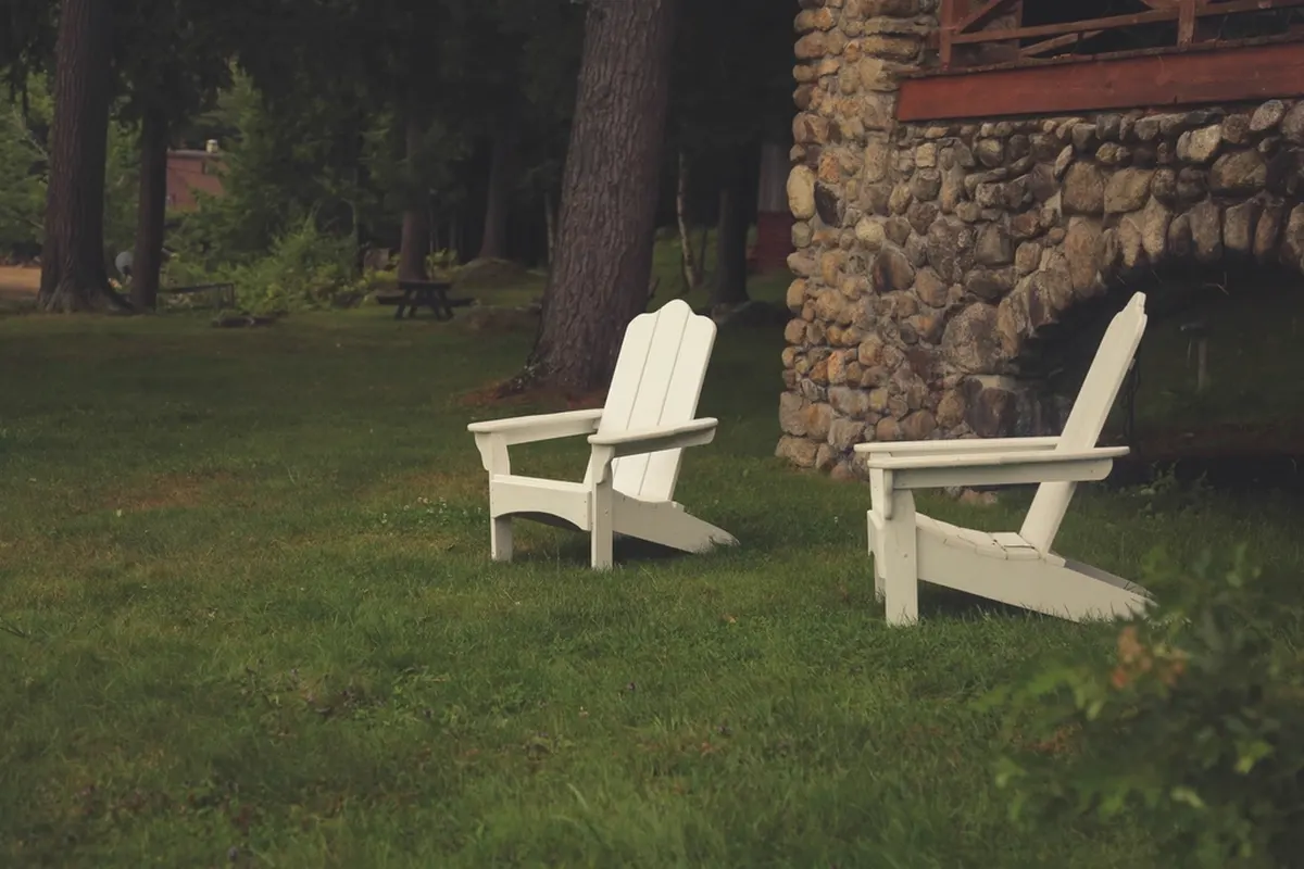 two white lawn chairs on a green backyard lawn