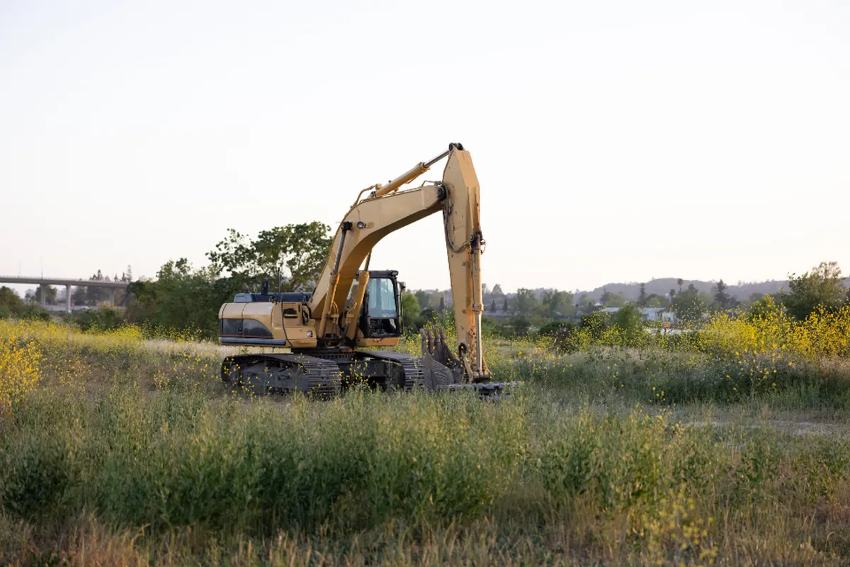 excavator on an open field at sunset