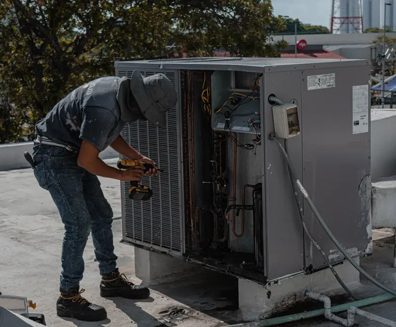 Technician checking refrigerant pressure on an AC condenser