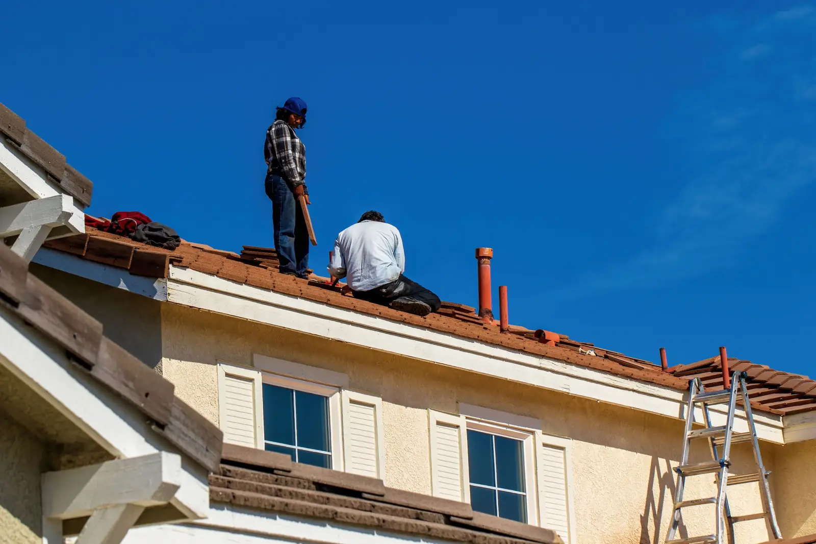 Summit crew working on the roof of a two-story home under a blue sky