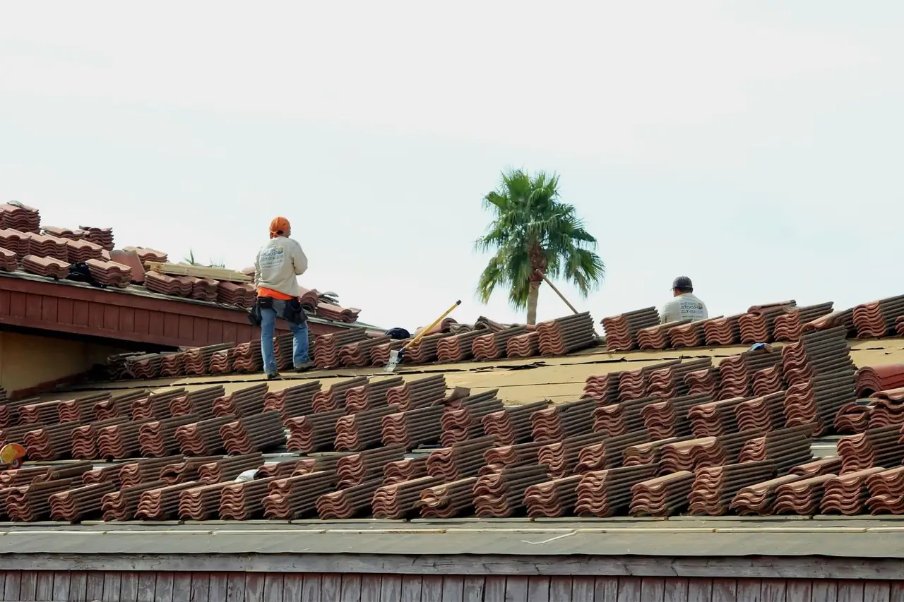 Summit roofing crew installing terracotta tiles on a home with a palm tree behind