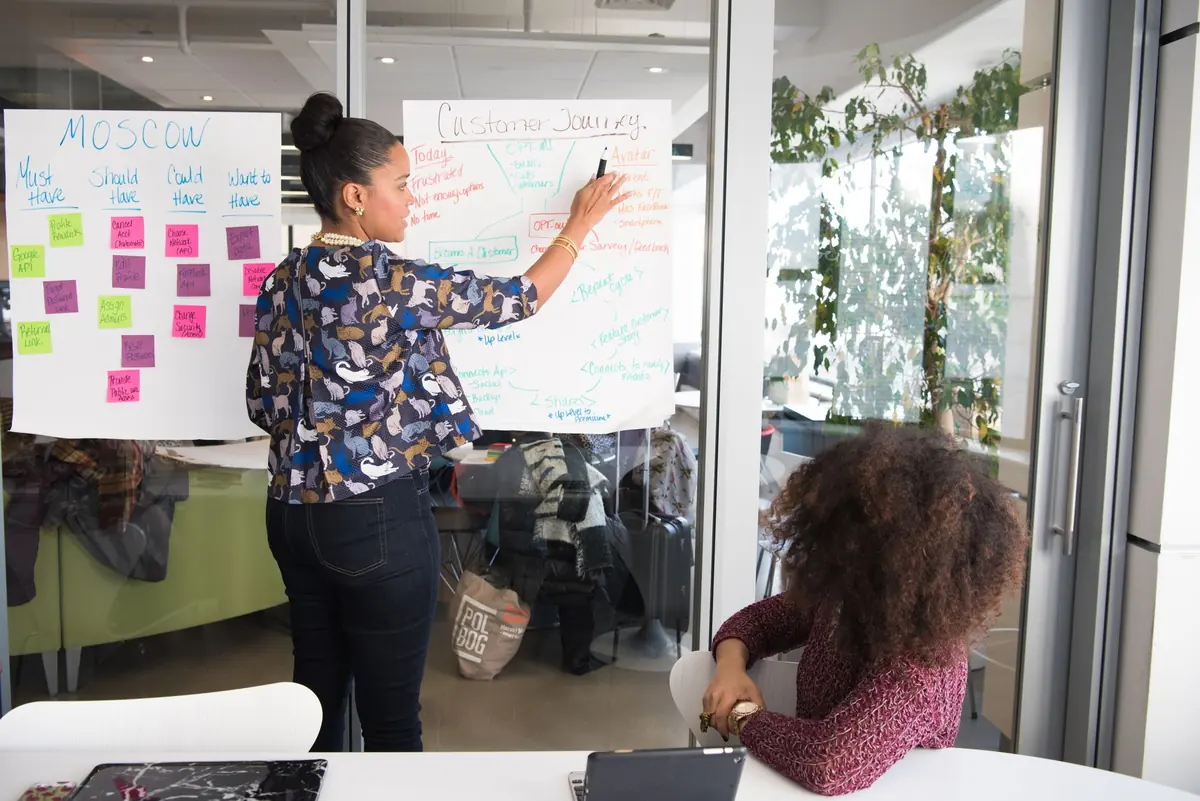 facilitator mapping ideas on a whiteboard covered in sticky notes during a workshop