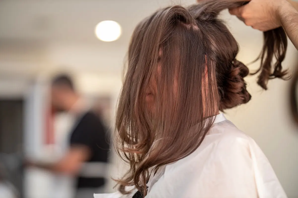 stylist sectioning long brown hair during an appointment