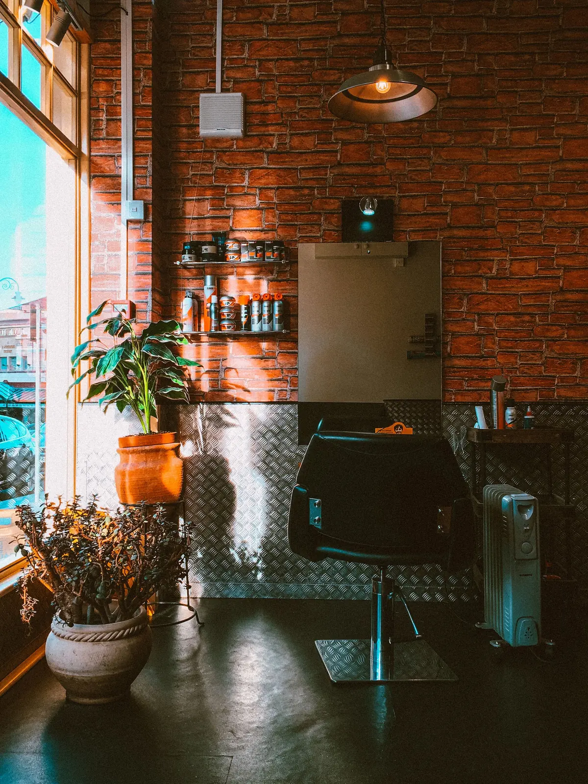styling chair and mirror beside a bright window in a salon with an exposed brick wall