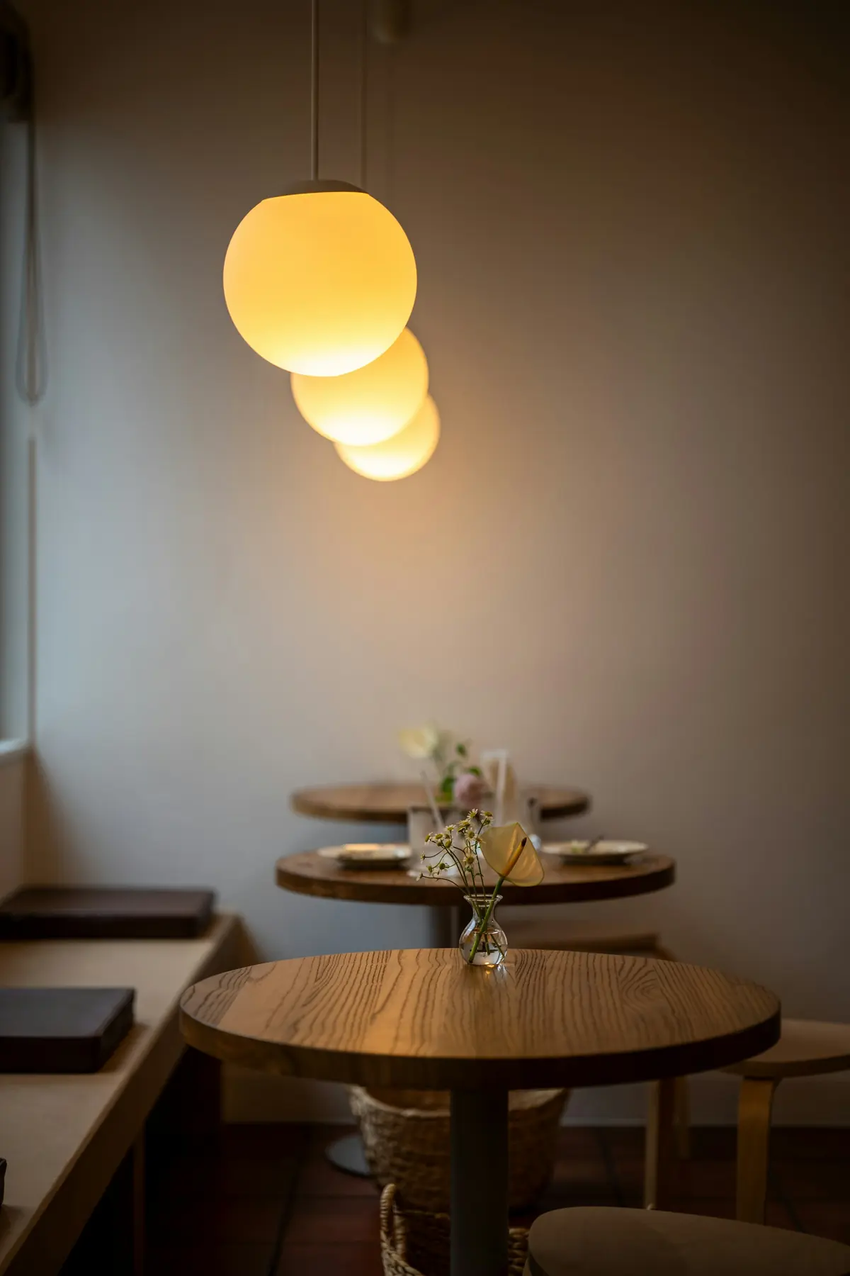 quiet corner of the dining room with round tables under warm globe pendant lights