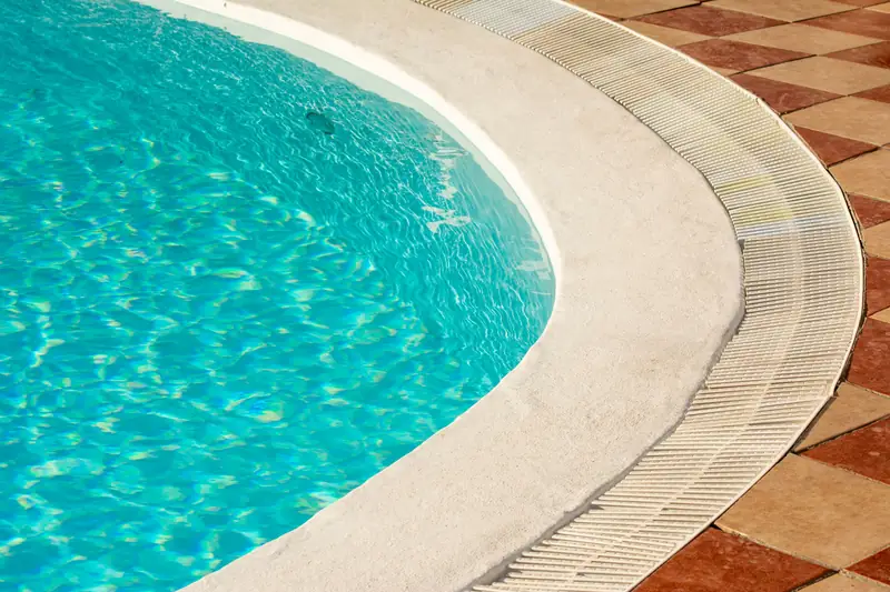 Close detail of sunlit pool water against travertine coping