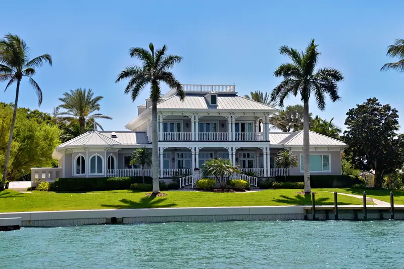 white waterfront estate with palms on a Naples canal