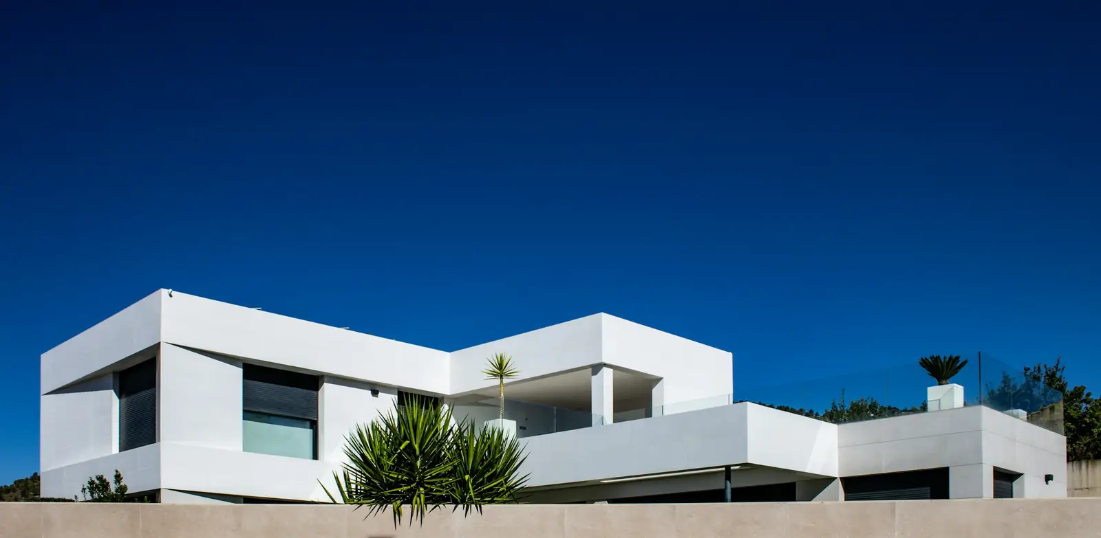 long, low white modern house under a dark blue sky