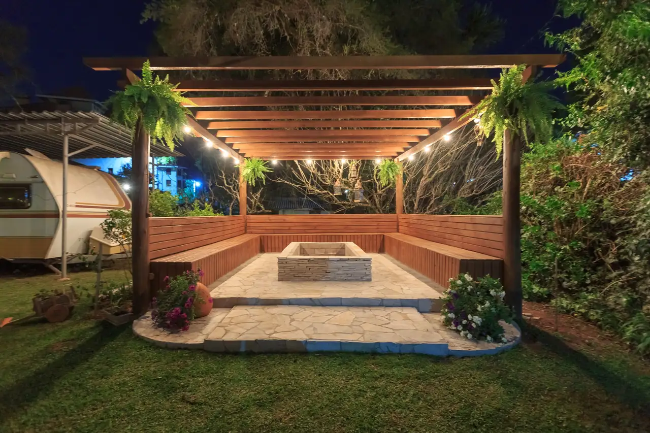 sunken fire pit lounge under a timber pergola with string lights at night