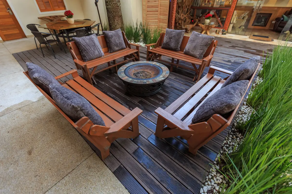 teak sofas around a round fire table on a timber deck