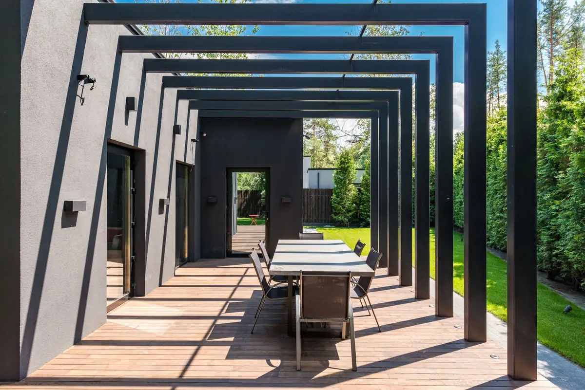 black steel pergola frames over a long outdoor dining table