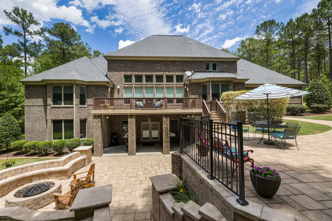 multi-level paver terrace with fire pit and seating behind a large home